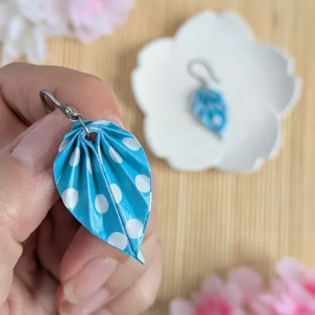 Gros plan sur les feuilles en origami à pois blancs qui composent les boucles d’oreilles.