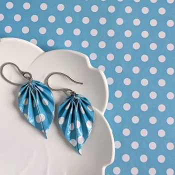 À côté des boucles d’oreilles, le papier origami à pois blancs utilisé pour façonner chaque feuille à la main.