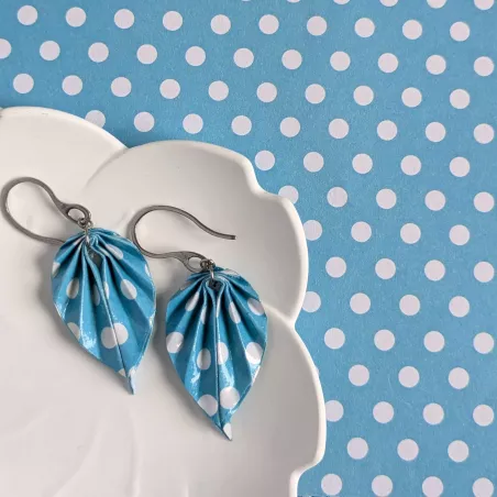 À côté des boucles d’oreilles, le papier origami à pois blancs utilisé pour façonner chaque feuille à la main.