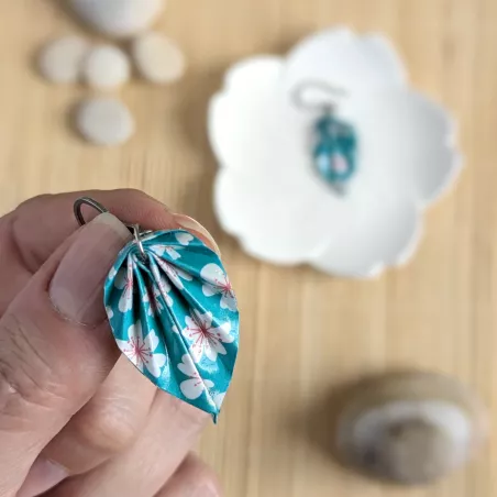 Détail des feuilles en papier origami et de leurs motifs sakura stylisés, aux lignes délicates.
